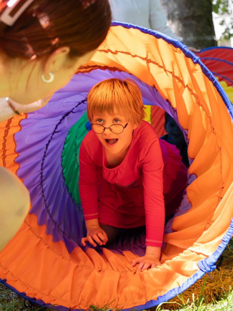 Deklica v pisanem tunelu, ki je del poligona na festivalu »Igraj se z mano«. Foto: Jakob Šircelj